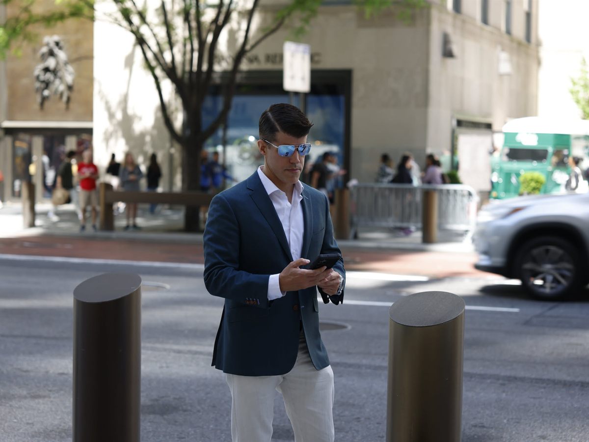 Man on a city sidewalk checking a text on his phone