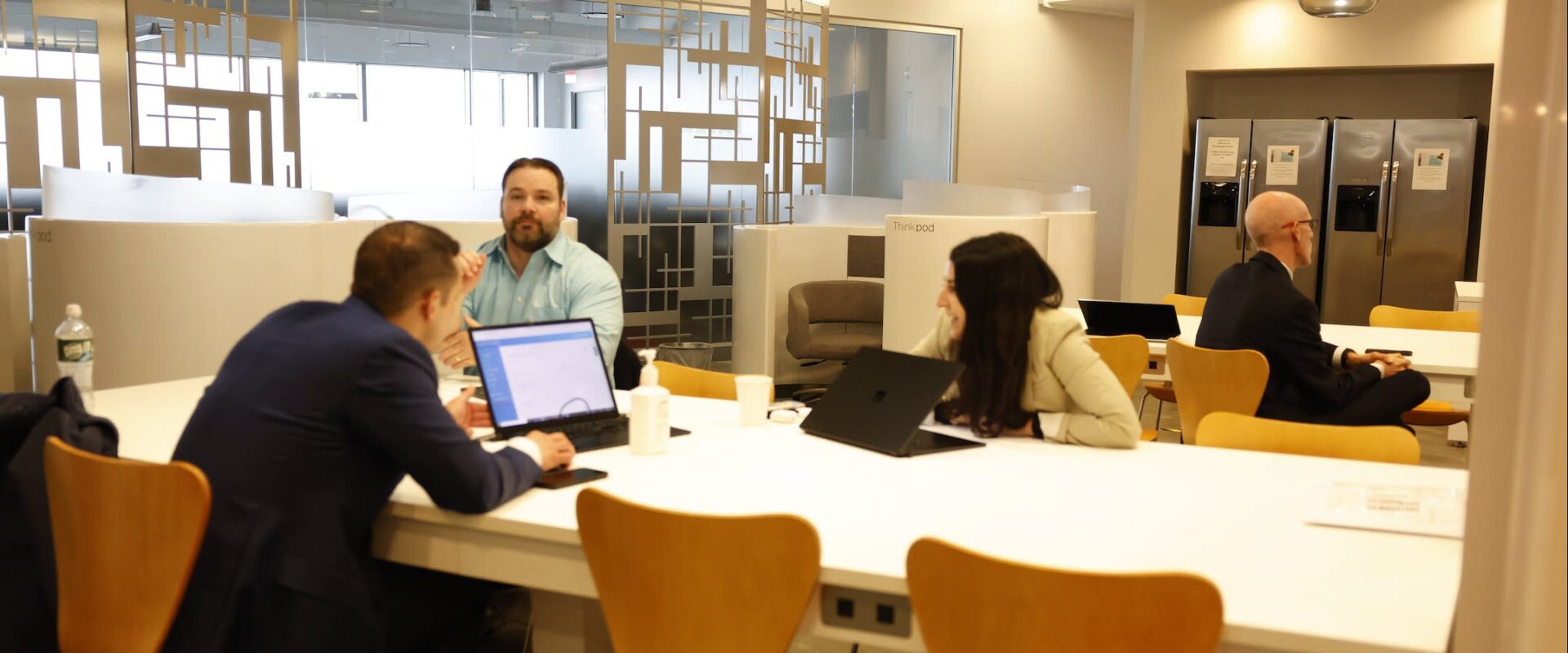 A team working on laptops around a shared table in an open office